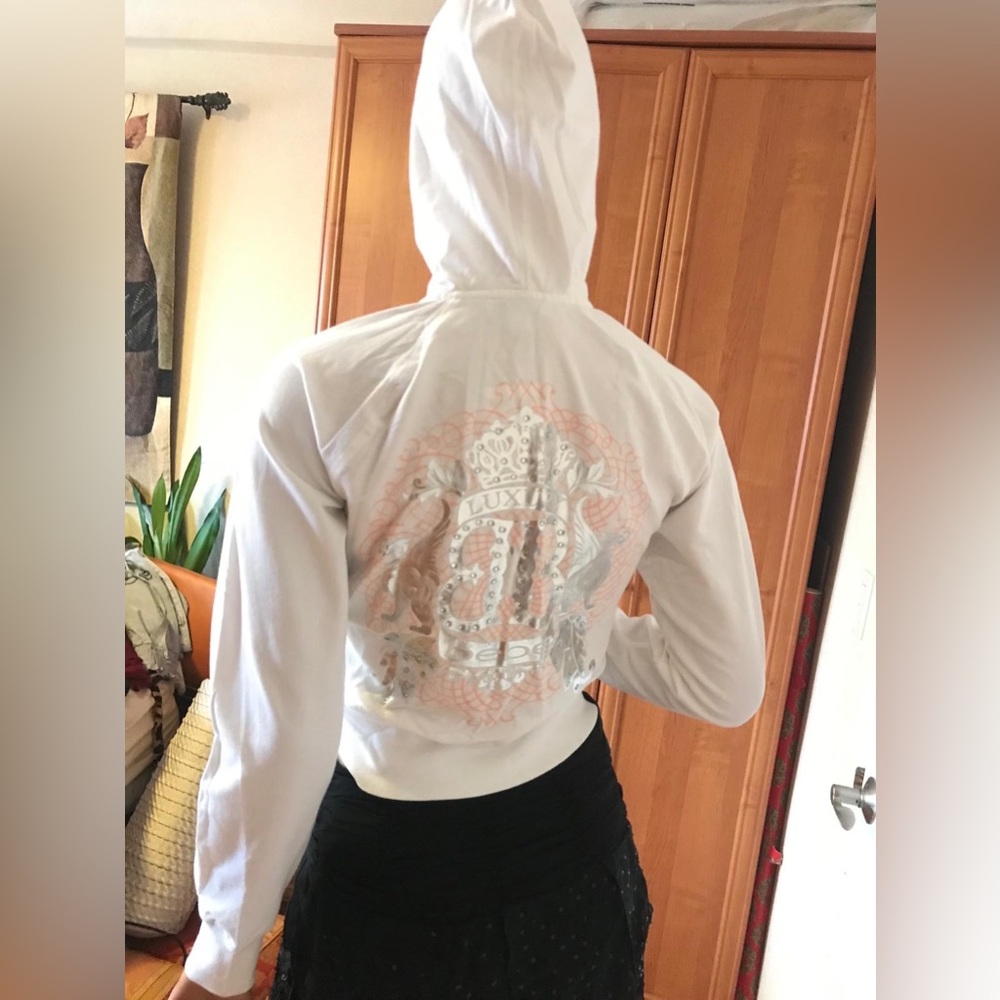 Bebe white hoodie with crystals and silver ornament in the back. NWT sz M.